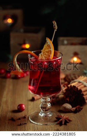 Christmas drink with spices, orange, and cranberries on an old wooden table.