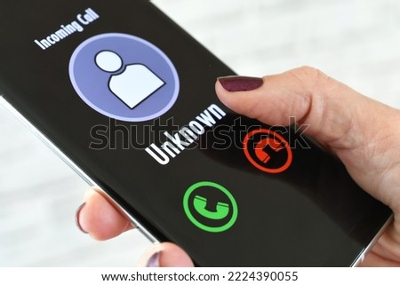 Hand holding cellphone with incoming call from Unknown Caller - fraud scam phishing Royalty-Free Stock Photo #2224390055