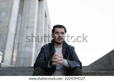frustrated depressed man looking into space while sitting on steps outside Royalty-Free Stock Photo #2224394127