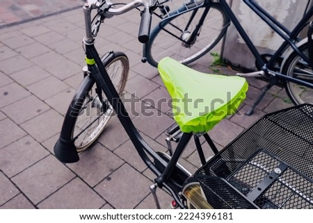rain cover on the seat or saddle of an urban bicycle Royalty-Free Stock Photo #2224396181