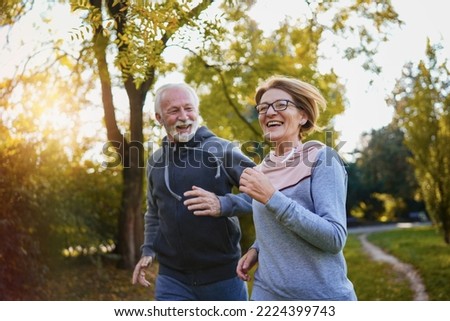 Cheerful active senior couple jogging in the park. Fitness routines for elderly people. Working out together. Exercise to stop aging.  Royalty-Free Stock Photo #2224399743