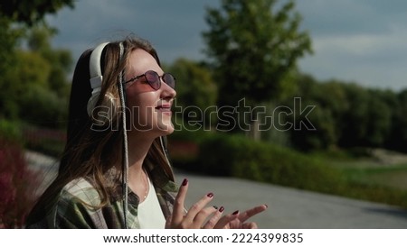 Young beautiful womanin casual clothes and sunglasses listening music with headphones outdoors