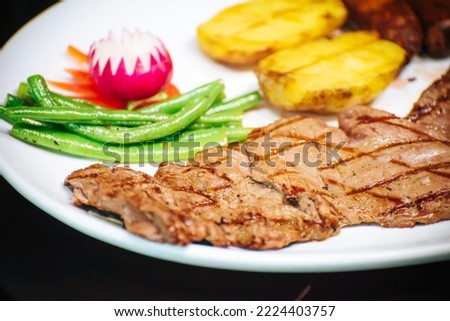 Delicious traditional barbecue dish. Grilled beef steak. Vegetables, string beans and potatoes. Healthy balanced meal. Traditional food.