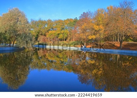 The photo was taken in the Ukrainian city of Odessa. The picture shows a lake, with reflected autumn trees, in a city park called Victory Park.
