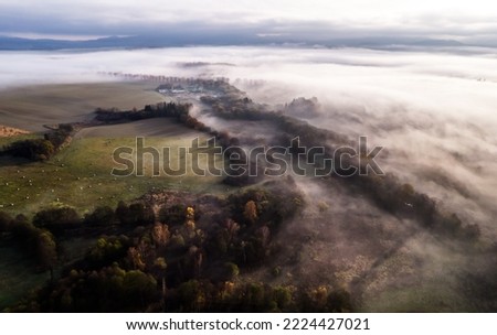 Aerial view of early morning mist in countryside of Poland with sunrays lighting over the autumn colored trees.