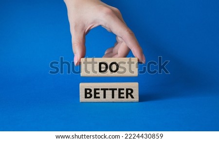 Do better symbol. Wooden blocks with words Do better. Beautiful blue background. Businessman hand. Business and Do better concept. Copy space.