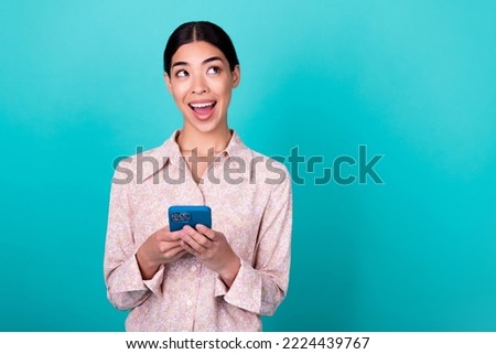 Photo of pretty positive vietnamese lady hold telephone look empty space isolated on aquamarine color background
