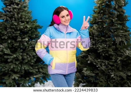 Photo of cheerful lady wear warm outerwear enjoy walk outside fresh air frosty day hand show v-sign isolated on blue color background