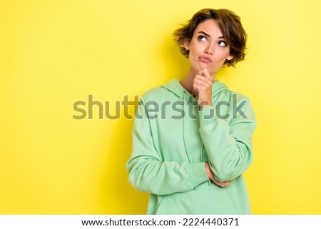 Photo portrait of pretty young woman look skeptical empty space unsatisfied wear trendy green clothes isolated on yellow color background