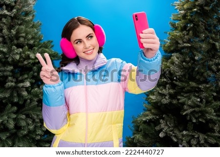Photo of joyful pretty lady wear stylish coat have fun walk outdoors street chatting followers make selfie picture hand demonstrate v-sign