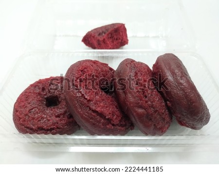 A pile of red donuts in the transparent container on white background 