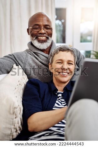 Were having a wonderful weekend indoors. Shot of an affectionate senior couple using a tablet while relaxing on the sofa at home. Royalty-Free Stock Photo #2224444543