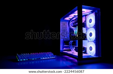 Water Cooled Gaming Pc with RGB rainbow LED lighting. Modern gaming computer with a keyboard in a dark room. Water Liquid Cooling Computer Royalty-Free Stock Photo #2224456087