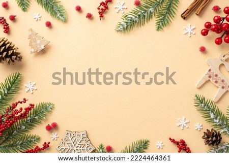 New Year concept. Top view photo of wooden ornaments fir branches in frost pine cones cinnamon sticks mistletoe berries and snowflakes on isolated beige background with blank space in the middle