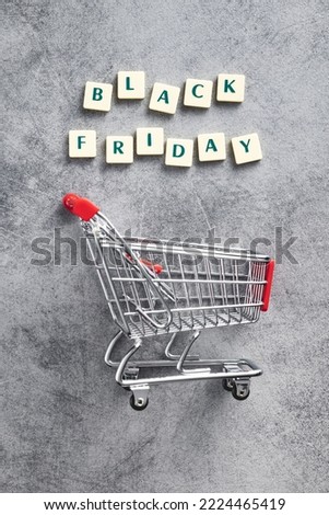 Black friday text and shopping cart on the gray background. Top view.
