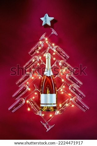 Silhouette of celebratory tree, a bottle of champagne surrounded by glasses and stars on red background. Merry Christmas and Happy New Year concept