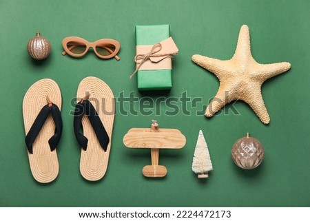 Travel accessories with Christmas decor and gift on green background