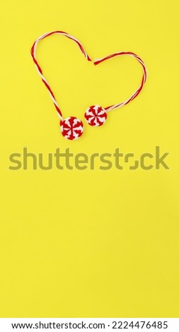 banner handmade red white round candy caramel two pieces lie heart on yellow background, copy space, vertical, 16:9