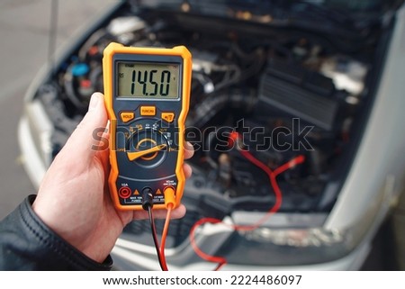 Checking car battery with digital multimeter. Check car battery using voltmeter. Man check up voltage level, alternator produce 14.5 volts with the engine idling. Winter service maintenance Royalty-Free Stock Photo #2224486097