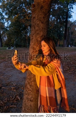 Portrait of Young woman taking a selfie in autumn at city park