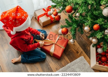 New Year's and Christmas. The boy unties the bow and opens the box with a Christmas present