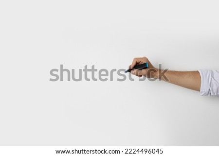 Man's hand holding a marker on a white background. Top view, flat lay.