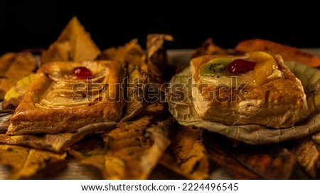 Puff pastry cakes with fruits on a layer of leaves with the colors of autumn