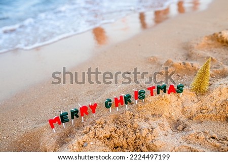 Vacation by the sea. Celebration of the traditional December holiday near the ocean. The text of a Merry Christmas made of candles next to the foaming wave.