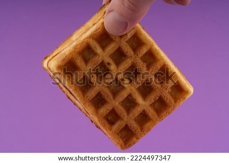 Hand holding a waffle in your hand. Closeup