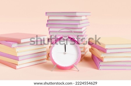 alarm clock placed near textbooks stacked against soft background