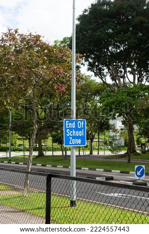 End of School Zone sign near a primary school in Singapore. Park and residential area in a background with a nice summer weather.