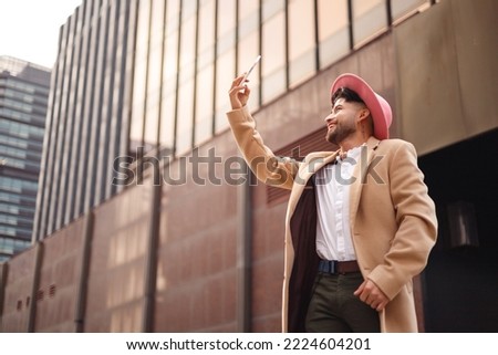 young latin man taking selfie in modern district outdoors, directly below shot, copy space
