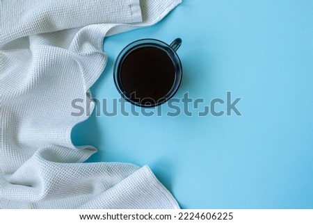 simple  minimalism image of a cup of coffee and a blanket on a blue background. top view. copy space. flat lay