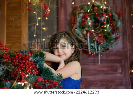 Baby girl in festive attire is in the room decorated for the new year and Christmas. The concept of holidays and gifts.