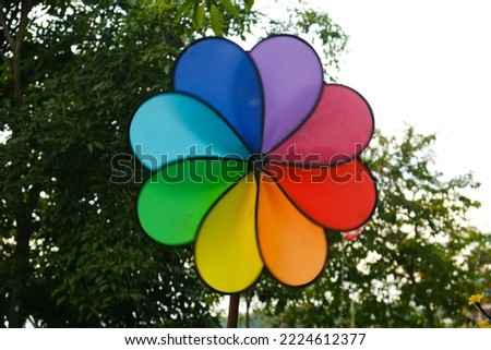 Selective focus picture of motion blur spinning colourful windmill at the park