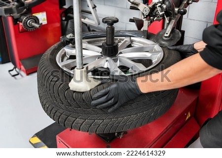 From above crop male worker of garage in gloves dismantling tire from rim using special machinery Royalty-Free Stock Photo #2224614329