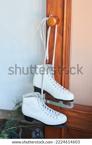 White ice skates hang on the door handle. Winter sports.