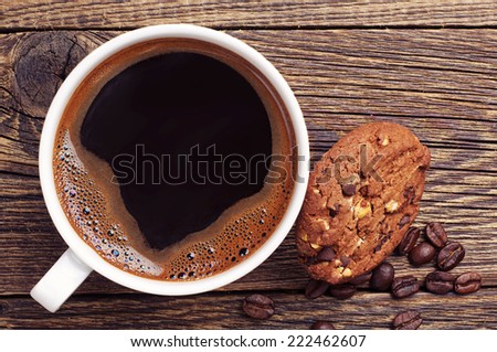 Closeup coffee cup and chocolate cookies with nuts on old wooden table. Top view