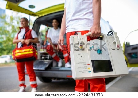 Hand of the doctor with defibrillator. Teams of the Emergency medical service are responding to an traffic accident. Royalty-Free Stock Photo #2224631373