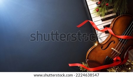 Christmas musical event concept background with piano and violin on black table and blue light. Top view.