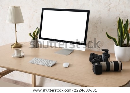 Photographer's workplace with computer and professional cameras near light wall