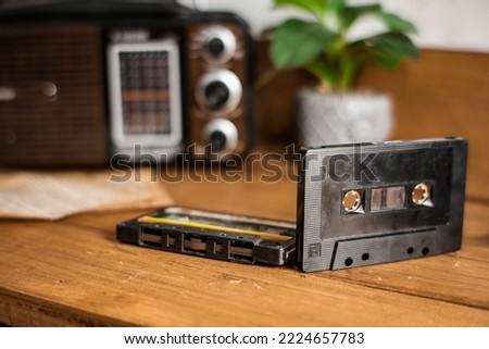 old blac tape cassette on wooden table against blurred old radio and vase Royalty-Free Stock Photo #2224657783