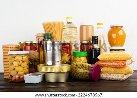 Emergency survival food set on dark wooden kitchen table Royalty-Free Stock Photo #2224678567