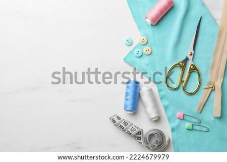 Threads and other sewing supplies on white marble table, flat lay. Space for text Royalty-Free Stock Photo #2224679979