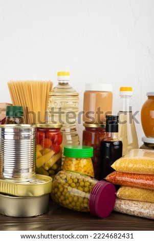 Emergency survival food set on dark wooden kitchen table Royalty-Free Stock Photo #2224682431