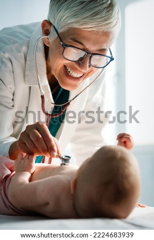 Happy pediatrician doctor with baby checking possible heart defect Royalty-Free Stock Photo #2224683939