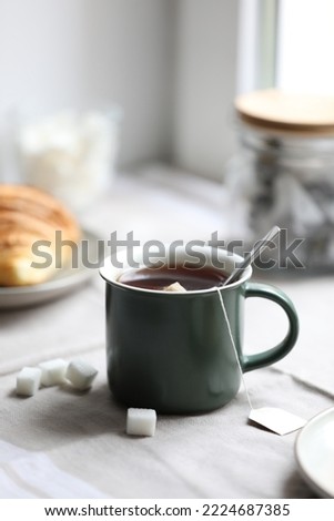 Cup of freshly brewed tea and sugar cubes on table Royalty-Free Stock Photo #2224687385