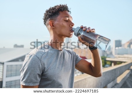 Fitness, exercise and man drinking water in city after running, training or cardio workout. Health, wellness and hydration of sports male from India resting or on break after marathon or sprinting. Royalty-Free Stock Photo #2224697185