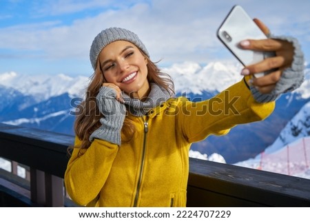 technology and leisure concept - happy woman in winter fur hat taking selfie by smartphone outdoors                      