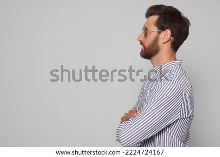 Profile portrait of bearded man with sunglasses on grey background. Space for text